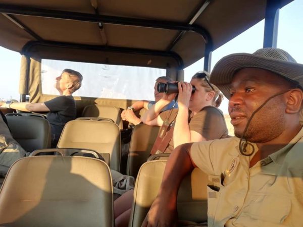A guest scanning the bush with binoculars from the vehicle